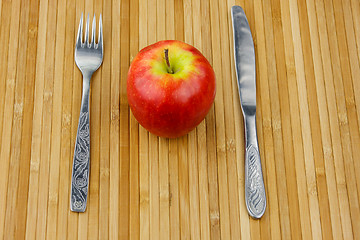 Image showing apple lying on a bamboo napkin with cutlery