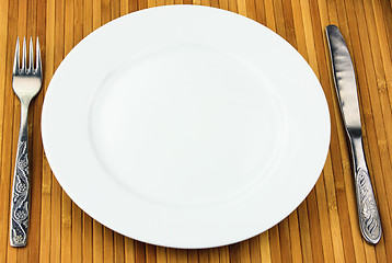 Image showing white plate, knife and fork at bamboo napkin