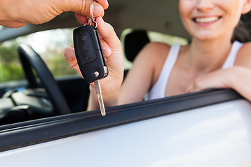 Image showing young smiling woman sitting in car taking key 