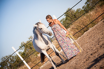 Image showing young woman walking a road with horse