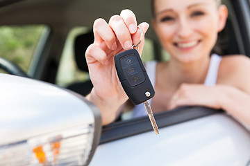 Image showing young smiling woman sitting in car taking key 