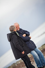 Image showing mature happy couple walking on beach in autumn