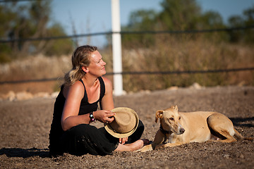 Image showing smiling blonde woman sitting outdoor with her dog