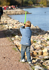 Image showing Boy playing on the river bank with a sword