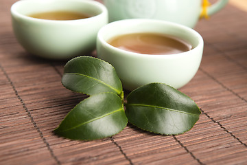 Image showing A cup of green tea with freh leaves