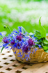 Image showing Bunch of cornflowers in a wicker basket. Summer background