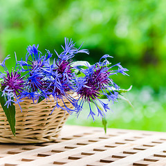 Image showing Bunch of cornflowers in a wicker basket. Summer background