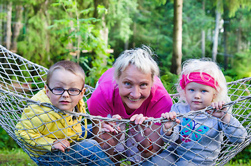 Image showing Children with grandmother swinging in a hammock, close-up  