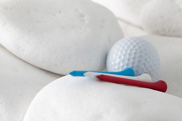 Image showing Golf ball and tees between white stones