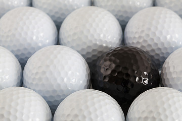 Image showing White golf balls and one black ball