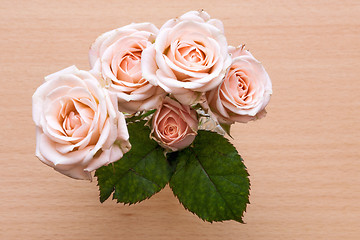 Image showing pink roses in a vase on a wooden desk