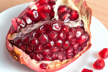 Image showing The cut pomegranate and grains on a plate