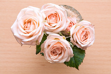 Image showing pink roses in a vase on a wooden desk