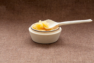 Image showing Pot of honey and wooden dipper on a cloth