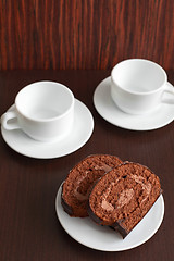 Image showing chocolate cake on a plate with a cup