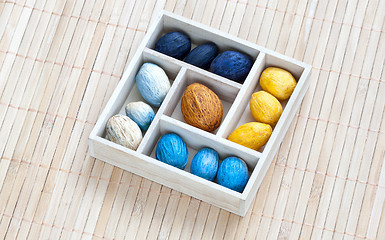 Image showing Box with colored nuts on a bamboo napkin