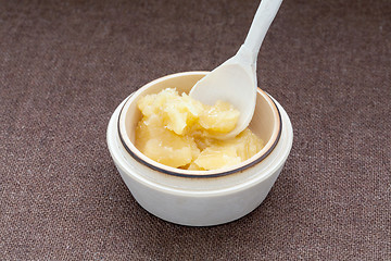 Image showing Pot of honey and wooden dipper on a cloth