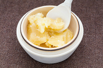 Image showing Pot of honey and wooden spoon on a bagging