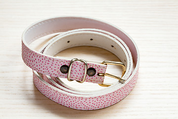 Image showing pink women style belt on a light wooden background