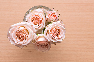 Image showing pink roses in a vase on a wooden desk