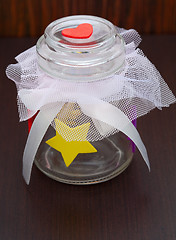 Image showing empty jar with a bow on a wooden background