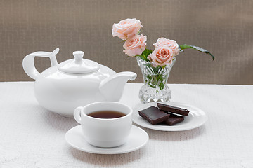 Image showing teapot, cup, roses, and chocolate on a plate