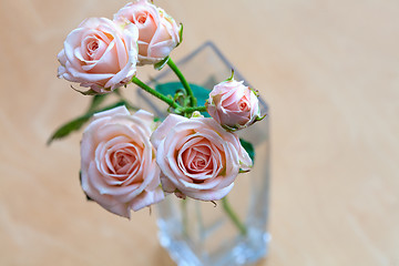 Image showing pink roses in a vase on a wooden desk