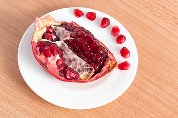 Image showing The cut pomegranate and grains on a plate