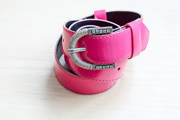 Image showing A pink women belts on a light wooden background