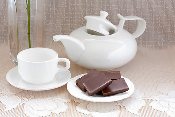 Image showing teapot, cup and chocolate on a plate