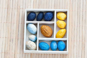 Image showing Box with colored nuts on a bamboo napkin