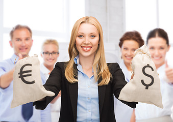 Image showing businesswoman holding money bags with dollars
