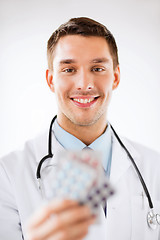 Image showing young male doctor with packs of pills