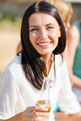 Image showing girl with drink and friends on the beach