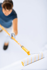 Image showing woman with roller and paint colouring the wall