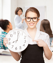 Image showing attractive student pointing at clock