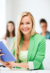 Image showing smiling young girl reading book at school