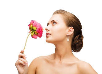 Image showing woman wearing earrings and smelling flower
