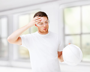 Image showing male architect in safety glasses taking off helmet