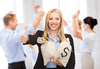 Image showing businesswoman with money bags showing thumbs up