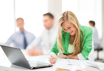 Image showing attractive businesswoman taking notes in office