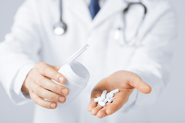 Image showing doctor hands holding white pack and pills