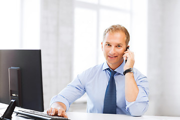 Image showing smiling businessman with smartphone in office