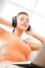 Image showing woman with headphones and laptop at home