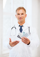 Image showing young male doctor with packs of pills