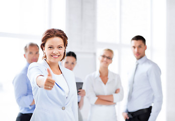 Image showing businesswoman in office showing thumbs up