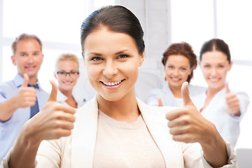 Image showing businesswoman showing thumbs up in office