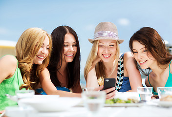 Image showing girls looking at smartphone in cafe on the beach