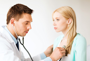 Image showing doctor with stethoscope listening to the patient