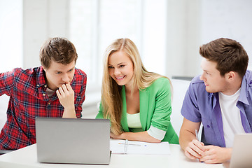 Image showing smiling students looking at laptop at school